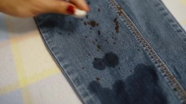 A woman cleans her pants from stains with a special tool. The concept of cleaning clothes.