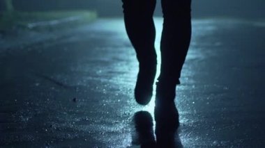 Büyük bir şehrin sokaklarında gece vakti arka planda yürüyen bir adamın bacakları. Bir yayaydı. Hotba. Şehir hayatı. Ön görünüm