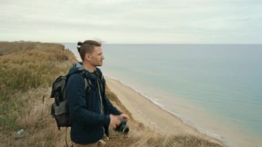 A professional photographer takes pictures on a SLR camera, picturesque landscape, travel.Satisfied with the result.A male photographer photographs a seascape