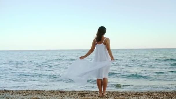 Young Girl White Dress Stands Alone Seashore Looks Distance She — стоковое видео