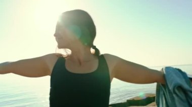 The girl rejoices at the view of the sea, raises her hands up and spins, smiling, looks into the camera. Rest, joy, travel. slow motion
