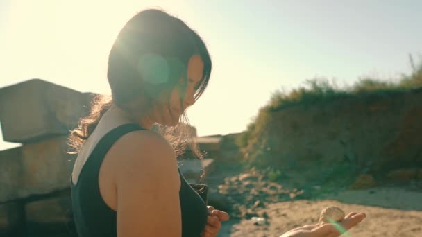 Young Woman Sitting Seashore Listens Sea Shell Fantasizes Active Rest — Vídeo de Stock