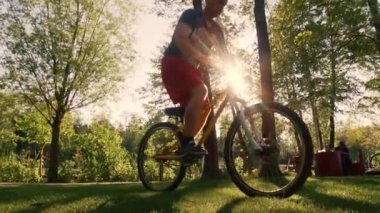 Bisikletli dublör etkili bir şekilde bisiklet üzerinde gösteri yapıyor. Gün batımında bir adam BMX 'in arka tekerleğinde bisiklet sürüyor. Aşırı, hareketli. Yavaş çekim