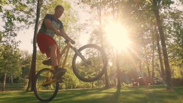 自行车特技表演者在自行车上有效地表演特技 一个男人在日落时骑着一辆Bmx的后轮骑自行车 极端的活动慢动作 — 图库视频影像