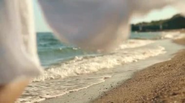 The girl runs barefoot along the sea coast. Close-up of womans legs running on sea waves on a sandy beach. Back view. Tourism. Leisure