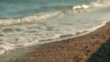Close-up of sea waves washing over a sandy beach. Calming waves of the beach