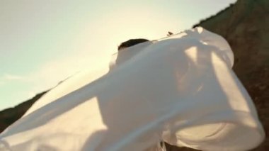 A happy girl rejoices in the wind that flutters the pareo with a sea view. The concept of freedom. Relaxation