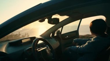 A young tourist girl gets out of the car to watch the sunset on the seashore. Trip, trip to nature. Leisure. Travel by car.