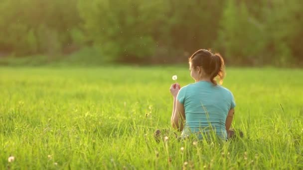Pretty Girl Blows Ripe Dandelion While Sitting Grass Evening Backdrop — Stok video