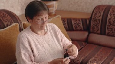 The woman opened a vial of healing liquid, poured it into a measuring spoon and diluted it in a glass of water. Home treatment. High quality 4k footage