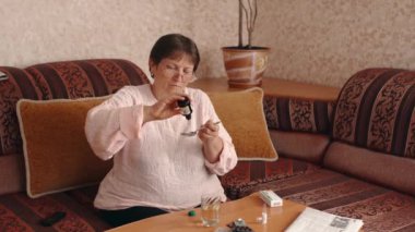 The woman opened a vial of healing liquid, poured it into a measuring spoon and diluted it in a glass of water and drank. Home treatment. High quality 4k footage