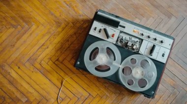 Top view of playback on an old reel-to-reel tape recorder against the background of old parquet. Retro tape recorder. Nostalgia. High quality 4k footage
