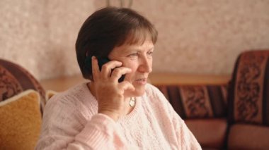 Woman chatting on mobile phone sharing news while relaxing alone in the living room. Leisure. 4K