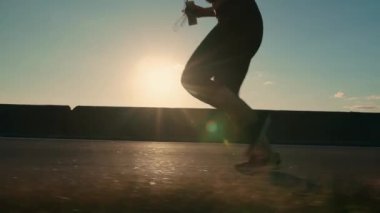 Woman running on the road at sunset. Silhouette of running female legs. Girl jogging, side view. Running endurance training.High quality 4k footage