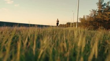 A young girl is engaged in sports jogging on the road against the background of the sky and grass. Healthy, active lifestyle.High quality 4k footage