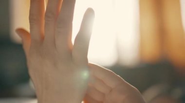 A young girl catches the rays of the sun from the window with her hands in the room. Womens hands close up.High quality 4k footage