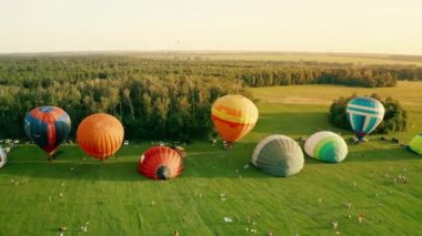 UKRAINE, Kolonshchyna - June 27, 2020: Balloon festival.Colorful hot air balloons are preparing to take off through the rays of the setting sun. Balloon festival. Ballooning.Aerial view. 4k