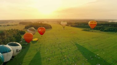 UKRAINE, Kolonshchyna - June 27, 2020: Balloon festival.Aerial view of hot air balloons flying over trees and fields. Fantastic summer sunset scene. High quality 4k footage