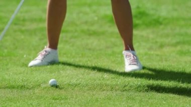 Bilinmeyen bir oyuncu golf sahasında golf oynuyor. Kendine güvenen sporcu kadın ısınıyor ve golf sopasıyla topa vuruyor. Açık hava eğlencesi ve spor konsepti.