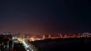 Gece trafiğinin alacakaranlıkta şehir sokaklarındaki zamanlaması. Yukarıdan bak. Gece yolu nehir boyunca hareket eden arabalarla dolu. Gece manzarası. Yüksek kalite 4k görüntü