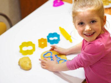 Mutfakta kız çocuğu zencefilli ekmek hazırlıyor. Sevimli komik çocuk ev yapımı tatlıyı pişirmeye hazırlıyor..