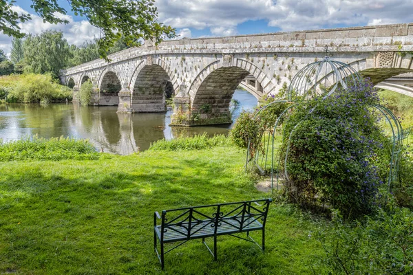 An old bridge over a river in England. This is an old bridge behind this bridge is a newer one.