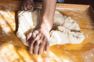 Yaşlı kadınların elleri ekmek hamuru yoğuruyor. Empanada 'lar. Tahta masa..