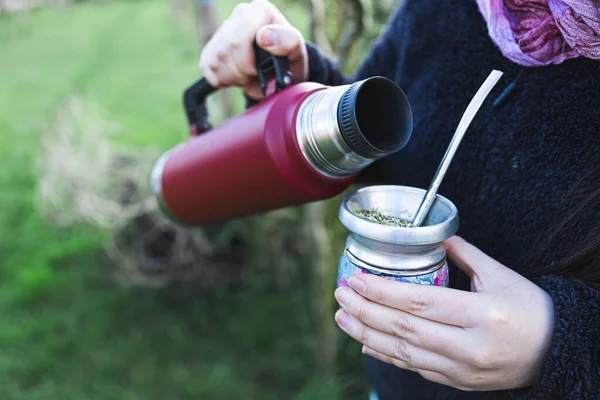 Mujer joven sirviendo mate en un espacio natural. Bebida latina. —  Fotos de Stock