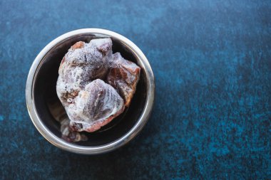 Mavi arka planda metalik bir kasede çiğ donmuş et. Yiyecek ve içecek konsepti