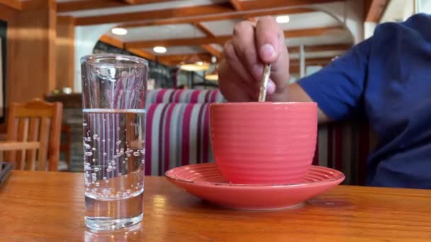 一个不认识的人在一家乡村咖啡屋里搅拌着咖啡，喝了第一口 — 图库视频影像