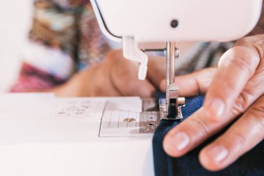 Giysi üretmek için dikiş makinesi kullanan tanınmamış bir kadın. İstihdam sorunları