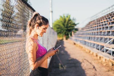 Güzel ve gülümseyen Kafkas genç aktif kadın koşmaya başlamadan önce akıllı telefonuna müzik listesi koyuyor..
