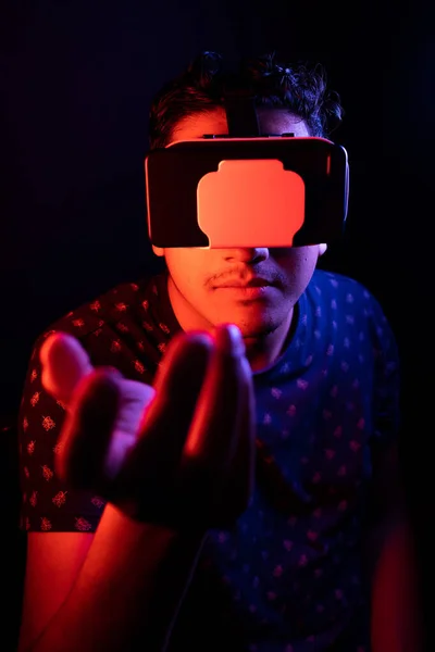 Молодий латинський чоловік використовує віртуальну реальність VR гарнітура 3D окуляри. Темний фон. Низький ключ . — стокове фото
