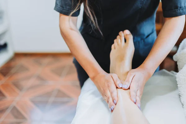 Terapeuta irreconocible haciendo un masaje de pies y piernas a una paciente femenina. Spa centro de bienestar. Cuidado de los pies. —  Fotos de Stock