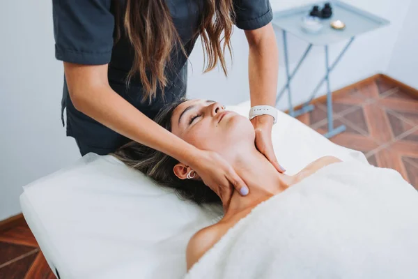 Женщина-терапевт делает массаж шеи пациентке с лицом вверх. Велнес-центр spa. Уход за кожей. — стоковое фото