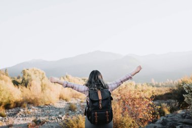 Sırt çantalı tanınmayan bir kadın zafer için kollarını kaldırıyor. Tek gezgin