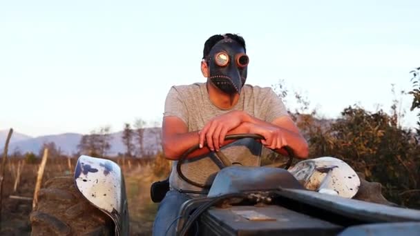 Bauer mit Pestmaske fährt alten Traktor auf seinem Acker. — Stockvideo