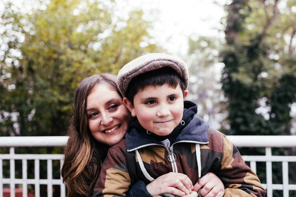 Single mother hugging her kid in the park. Single parent family. High quality photo. Copy space.