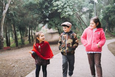 Üç çocuk, çekici kızlar ve parkta yürüyüp konuşan bir oğlan. Çocukluk