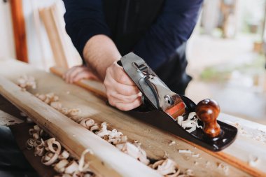 unrecognizable man using steel brush carpenter on a wooden stick, in his workshop. High quality photo