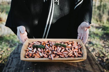 Geleneksel bir adam elinde Şili çam fıstığı, pehuen ve araucaria ağacı meyveli ahşap bir yalak tutuyor. Yüksek kalite fotoğraf