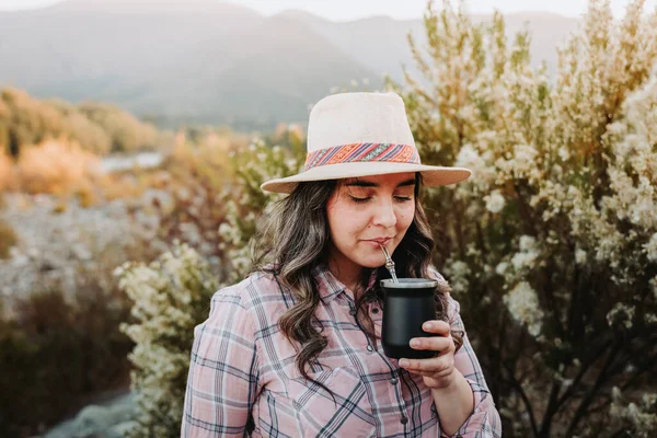 Young latin woman drinking yerba mate in a rural space Latin beverage. Ethnical concept. High quality photo. Horizontal