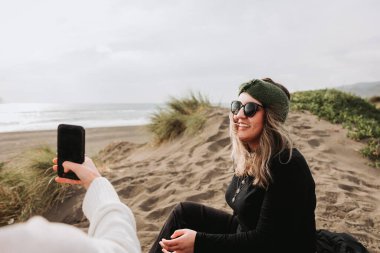 Two girls relaxing, sitting and taking theirself photos on the beach. Overcoming depression. High quality photo