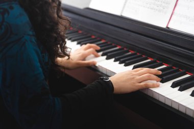 Unrecognizable womans hands playing piano by reading sheet music. High quality photo