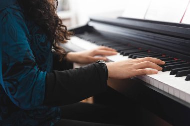 Close up of womans hands playing piano by reading sheet music. High quality photo