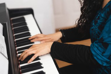 Close up of womans hands playing piano by reading sheet music. High quality photo