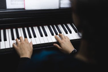 Close up of womans hands playing piano by reading sheet music. High quality photo