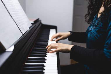 Close up of womans hands playing piano by reading sheet music. High quality photo