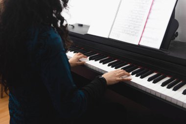 Close up of womans hands playing piano by reading sheet music. High quality photo