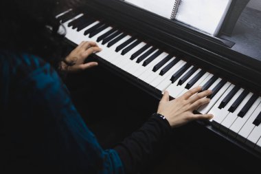 Close up of womans hands playing piano by reading sheet music. High quality photo